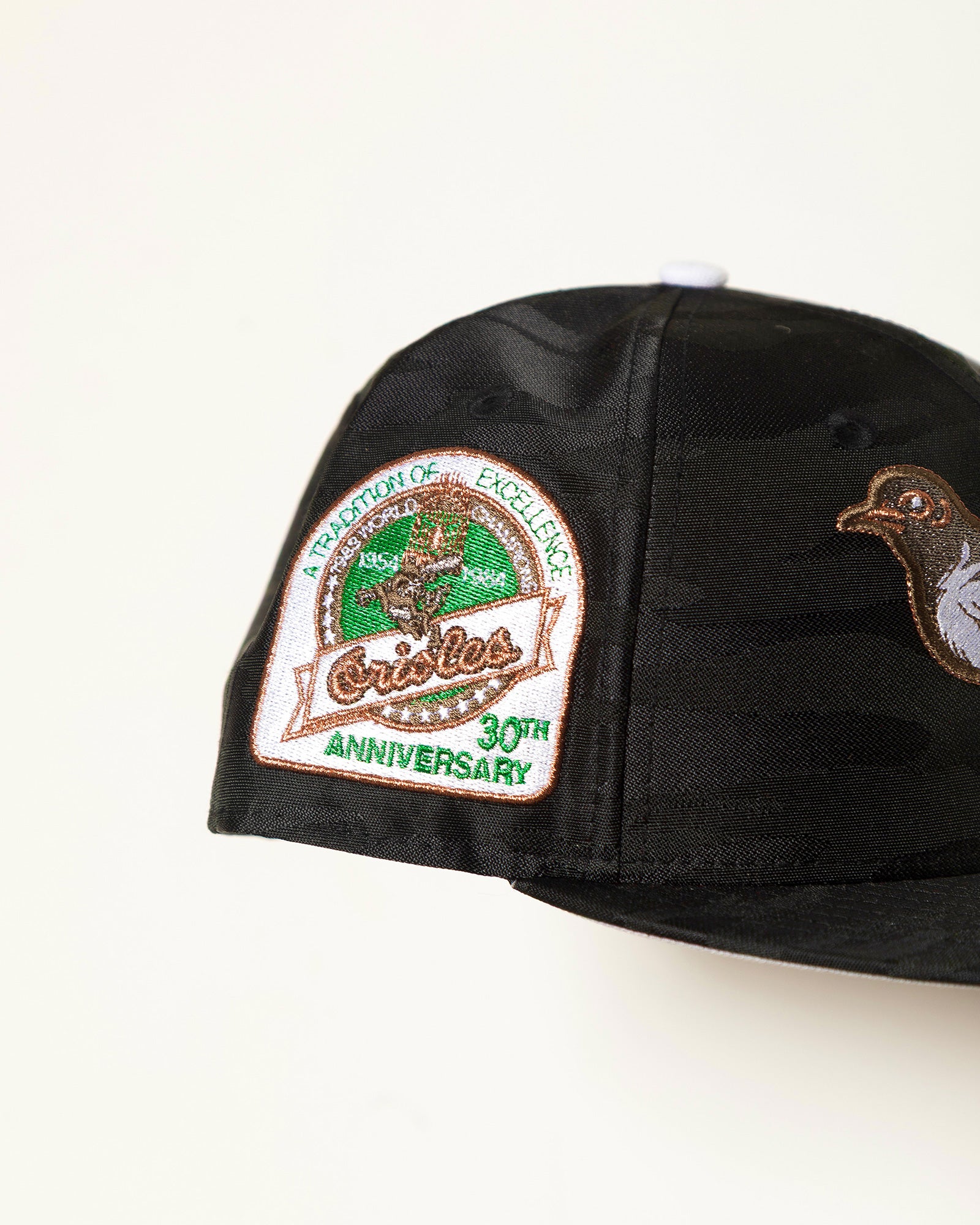 Highlark Baltimore Orioles 3.0 close detail, 30th Anniversary A Tradition of Excellence sidepatch in metallic copper and green on black camo crown