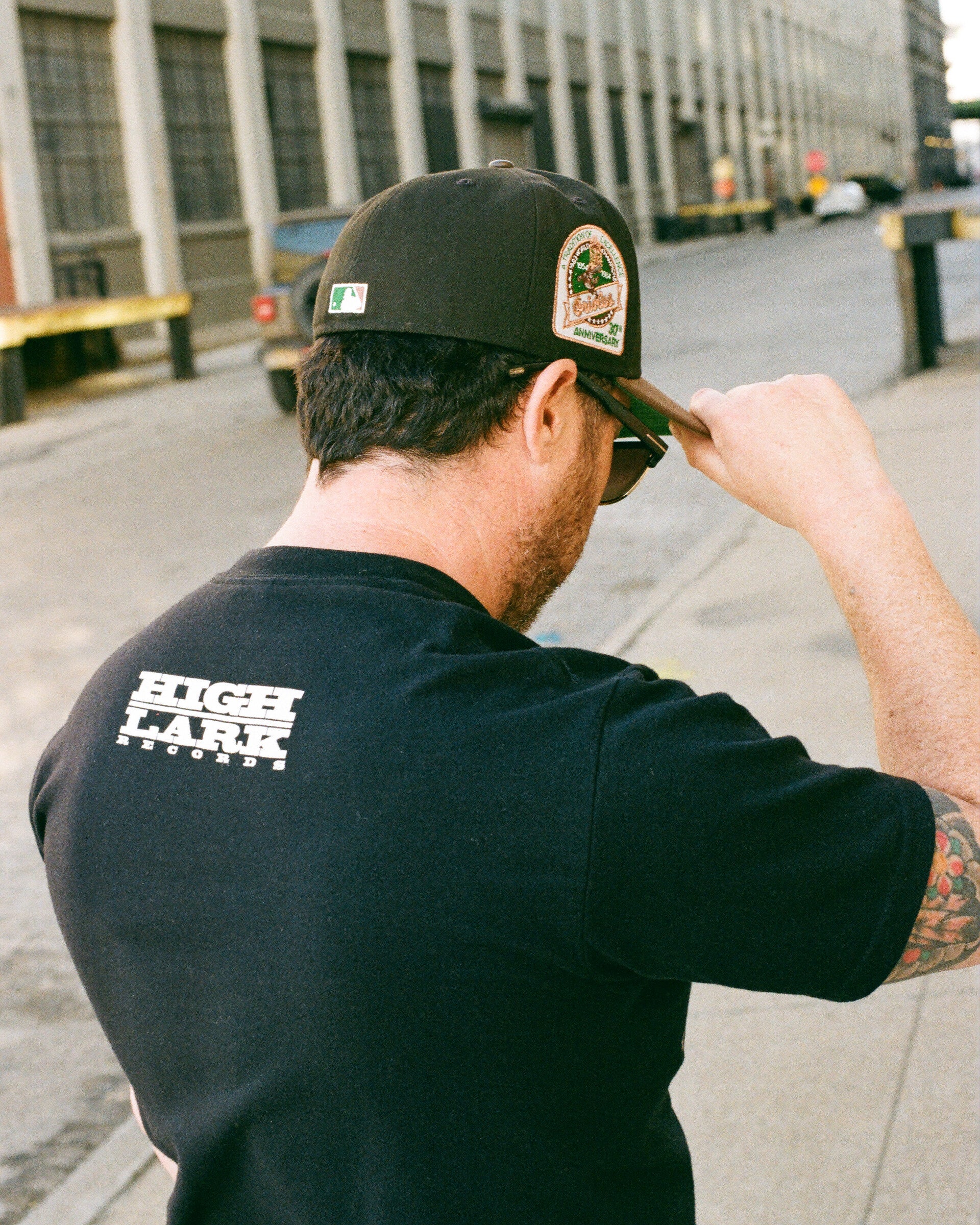 Brokerage stream: back of HIGH/LARK RECORDS tee, brim adjust, film texture